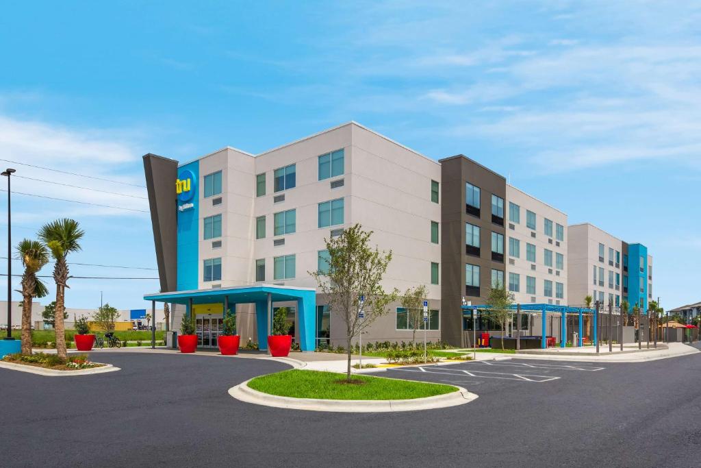 a large white building with palm trees in a parking lot at Tru By Hilton Destin in Destin