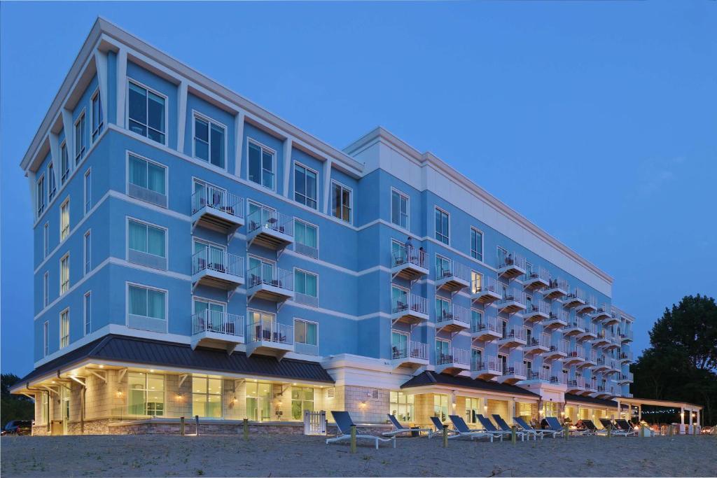 - un grand bâtiment bleu avec des chaises en face dans l'établissement Hampton Inn & Suites Manistee, Mi, à Manistee