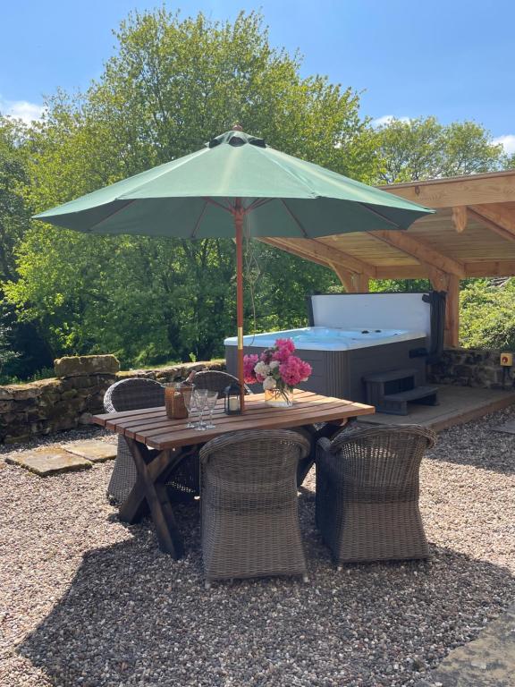 een picknicktafel met een groene parasol en stoelen bij Pond Cottage in Rosedale Abbey