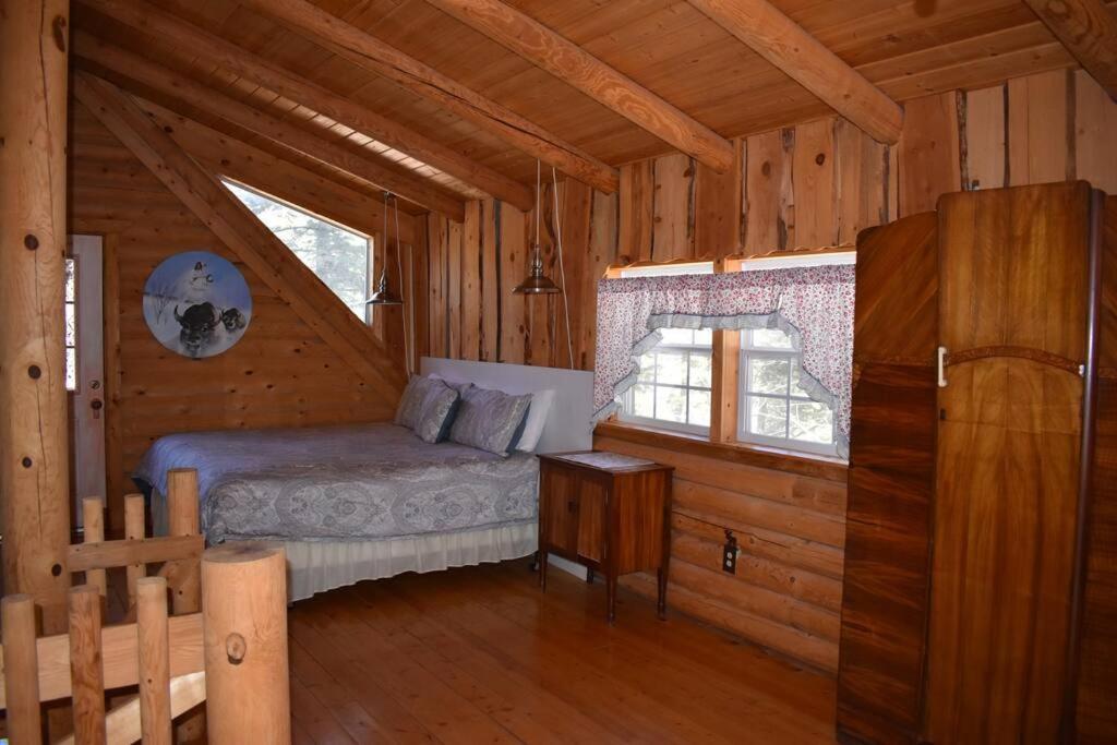 a bedroom in a log cabin with a bed and a window at Sky Cabin in Ruidoso