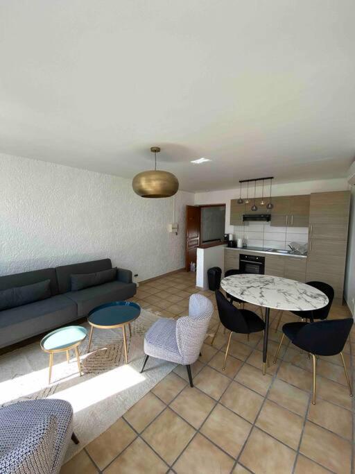 un salon avec un canapé, une table et des chaises dans l'établissement Appartement 2 pièces de charme climatisé, à Nîmes