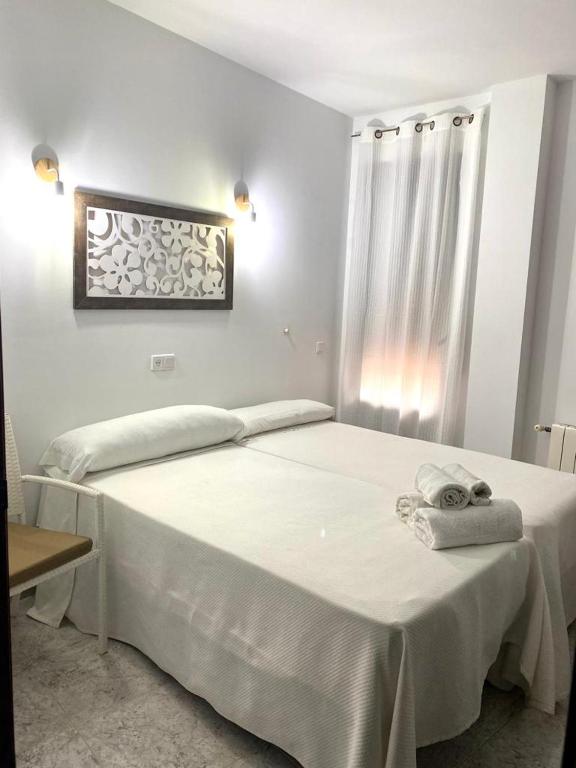 a bedroom with a white bed with a towel on it at Hostal Casa López in La Zarza