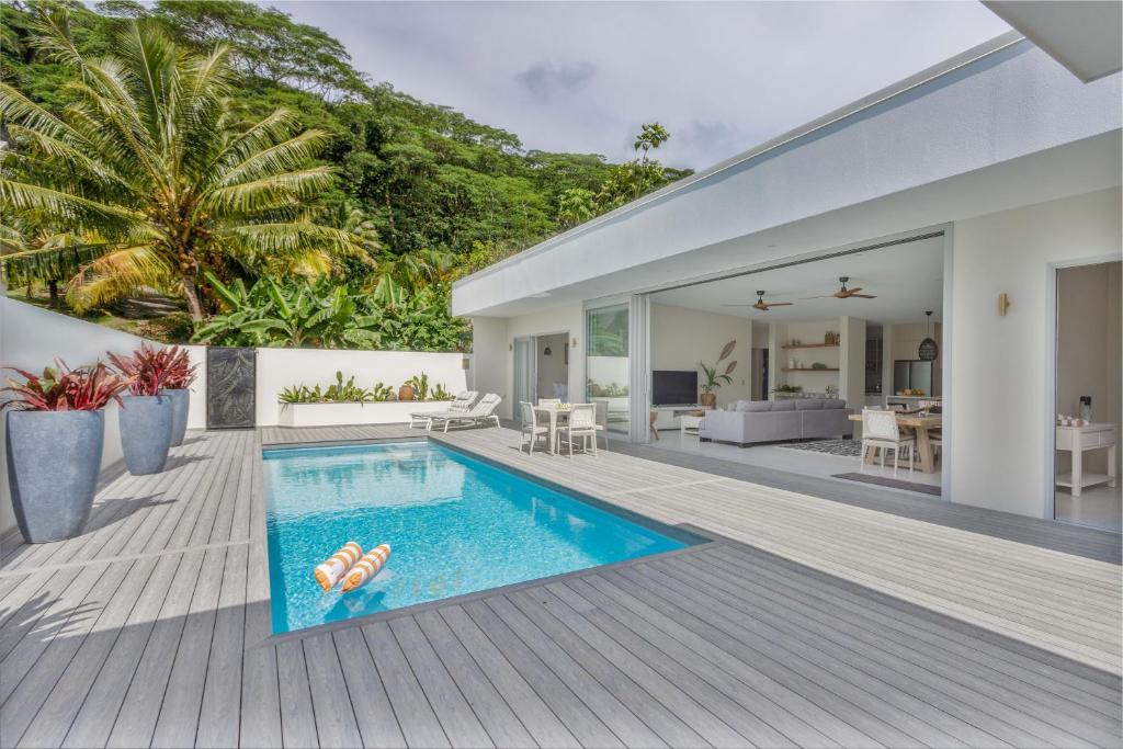 an open deck with a swimming pool and a house at Villa Varia in Rarotonga