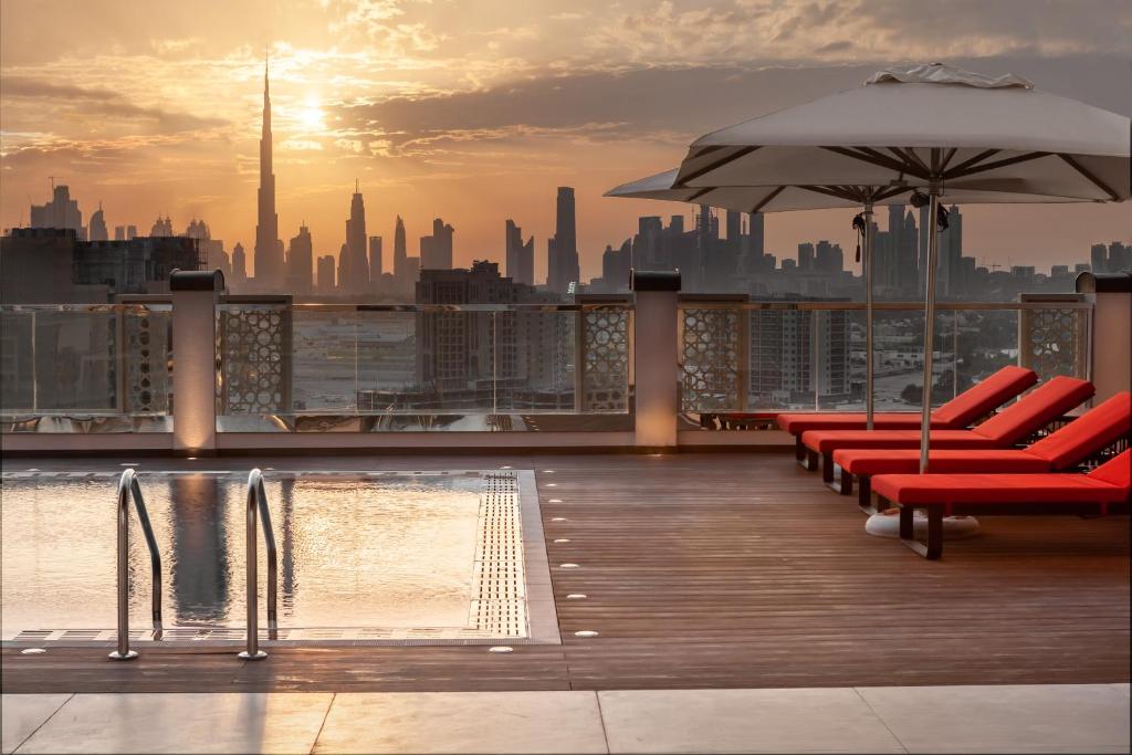 a rooftop deck with chairs and an umbrella and a city at DoubleTree by Hilton Dubai Al Jadaf in Dubai