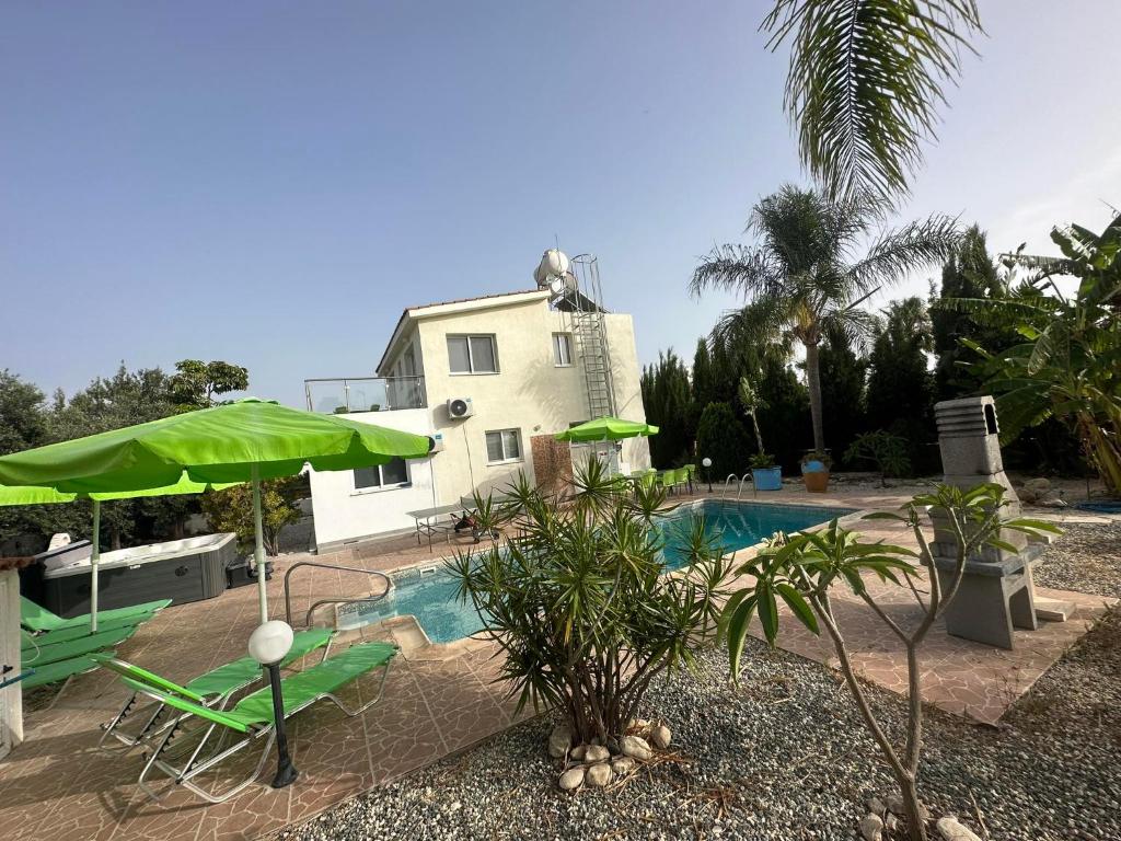 uma piscina com um guarda-sol verde e uma casa em Villa Coralia Gardens 1km From Coral Bay Beach em Coral Bay