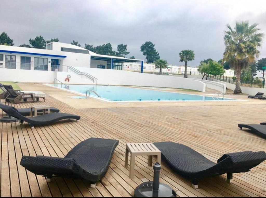 a swimming pool with lounge chairs on a deck at Pinhos Residence Palmela Village in Quinta do Anjo