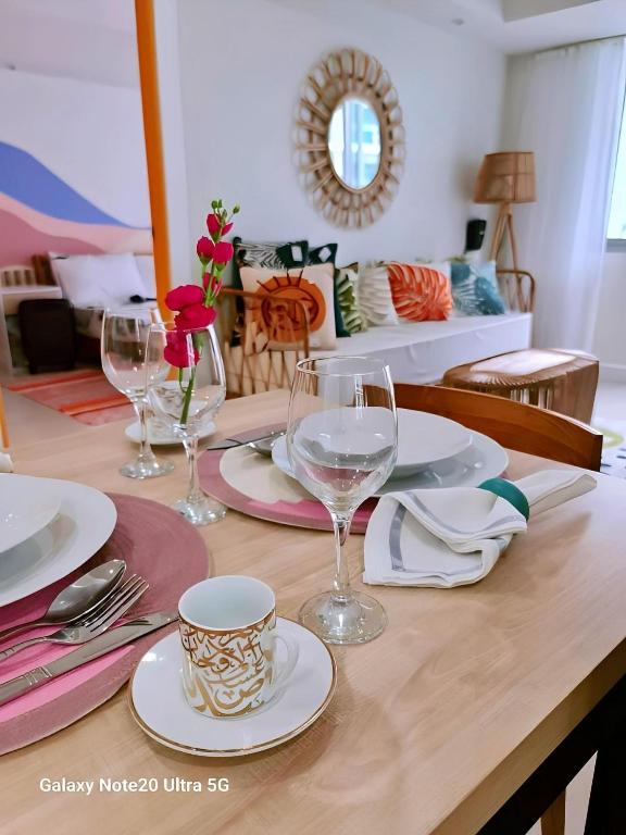a wooden table with wine glasses and plates on it at Manila Urban Resort at Azure in Manila