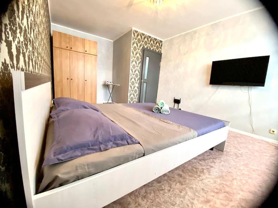 1 dormitorio con 1 cama grande y TV de pantalla plana en Апартаменты на 12 мкр, en Aktobe