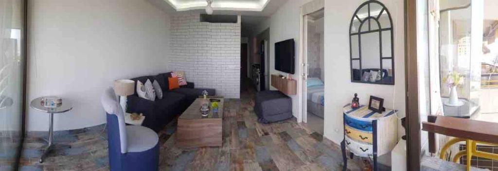 uma sala de estar com um sofá e uma televisão em Chalet In Solemar, 2br, Elec247, Parking, Wifi em Al Kaslīk