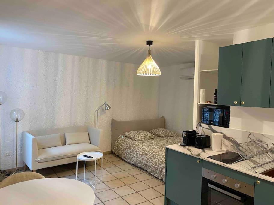 Cette chambre comprend un lit, un canapé et une cuisine. dans l'établissement Studio climatisé neuf centre-ville, à Nîmes