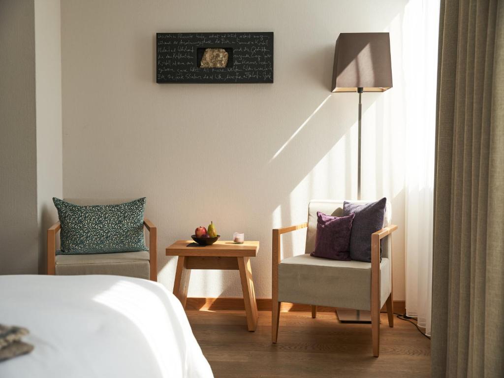 um quarto com uma cama, 2 cadeiras e uma mesa em Victoria - Alpine Boutique Hotel & Fine Dining em Meiringen