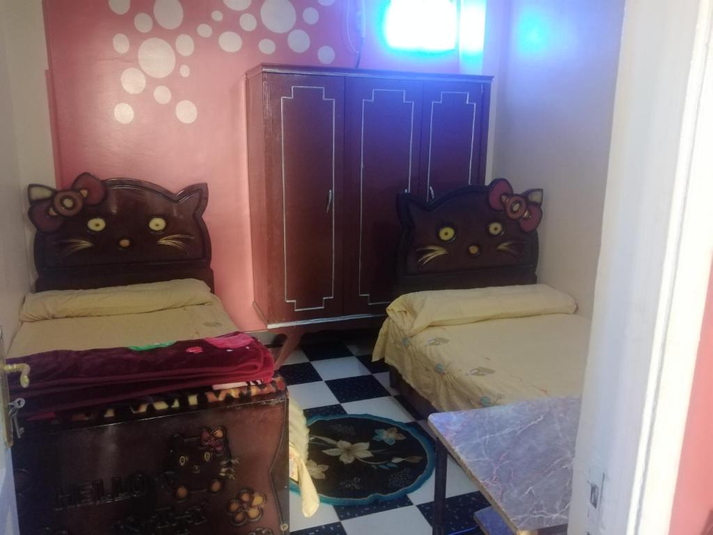 two beds in a room with two cats headboards at Hamody Nubian Guest House in Aswan