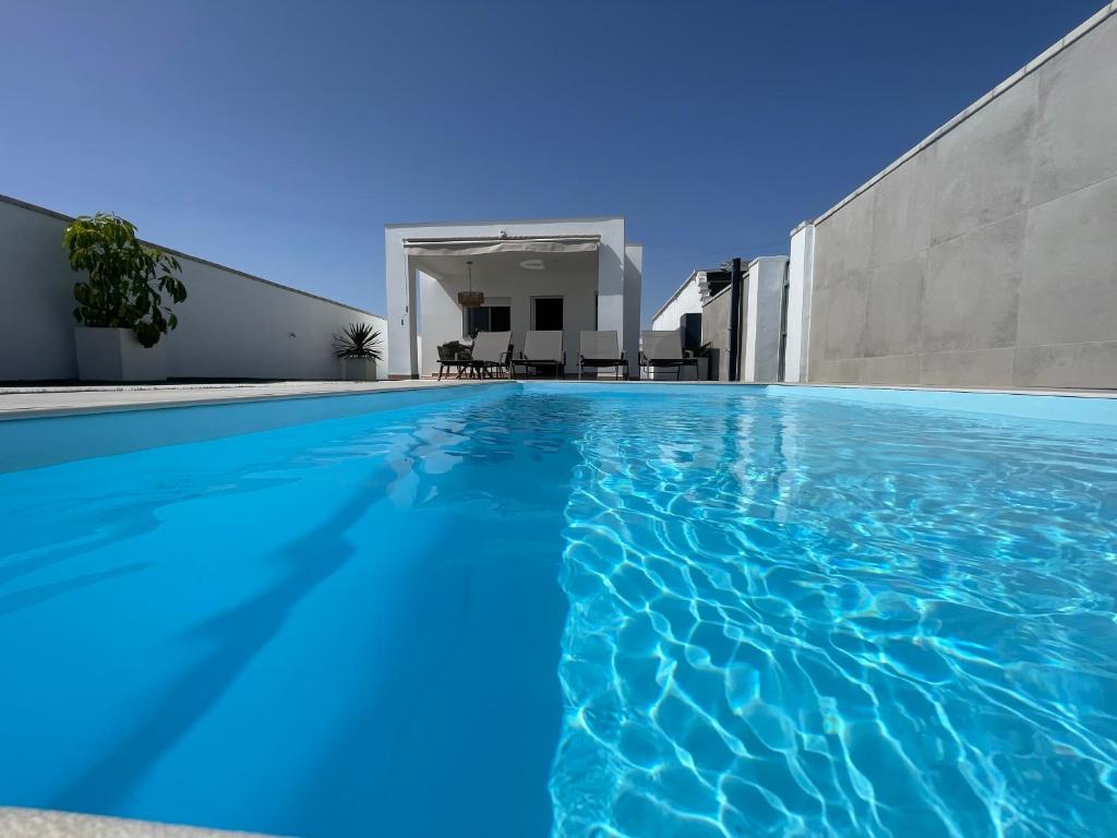 una piscina de agua azul frente a una casa en Casa Roche en Cádiz