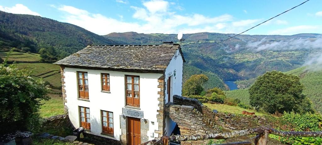 ein Haus auf einem Hügel mit Bergen im Hintergrund in der Unterkunft Apartamentos Rurales San Esteban de los Buitres - Illano 