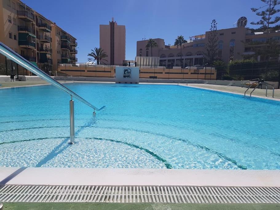 une grande piscine bleue avec des bâtiments en arrière-plan dans l'établissement Apartman Los Cristianos-Cristimar, à Los Cristianos