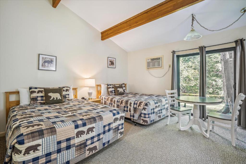 a bedroom with two beds and a table and a window at Cedarbrook Standard Hotel Room 105 in Killington