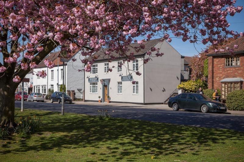 ein Baum mit rosa Blumen vor einem weißen Gebäude in der Unterkunft The Green Inn in Goole