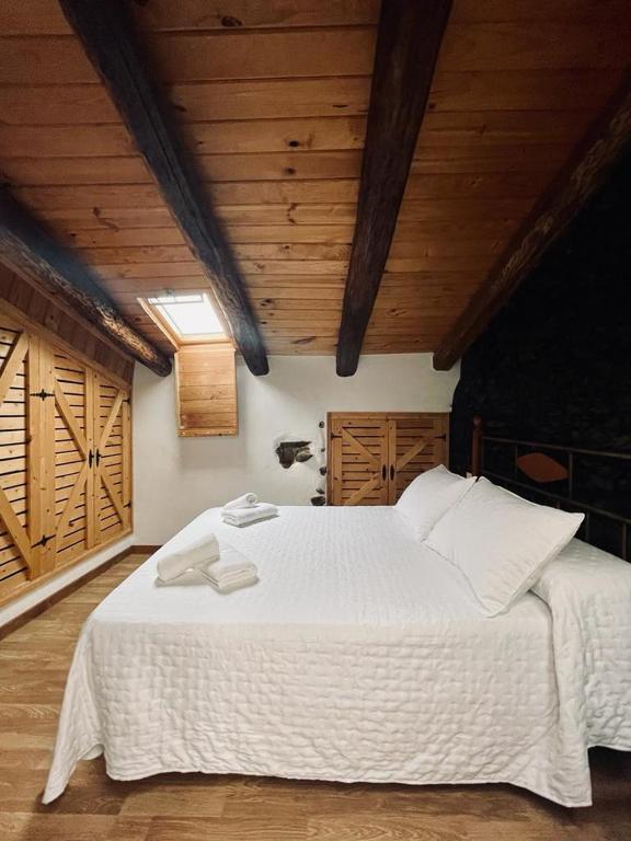 a large white bed in a room with wooden ceilings at La Casa del Castaño in Aracena