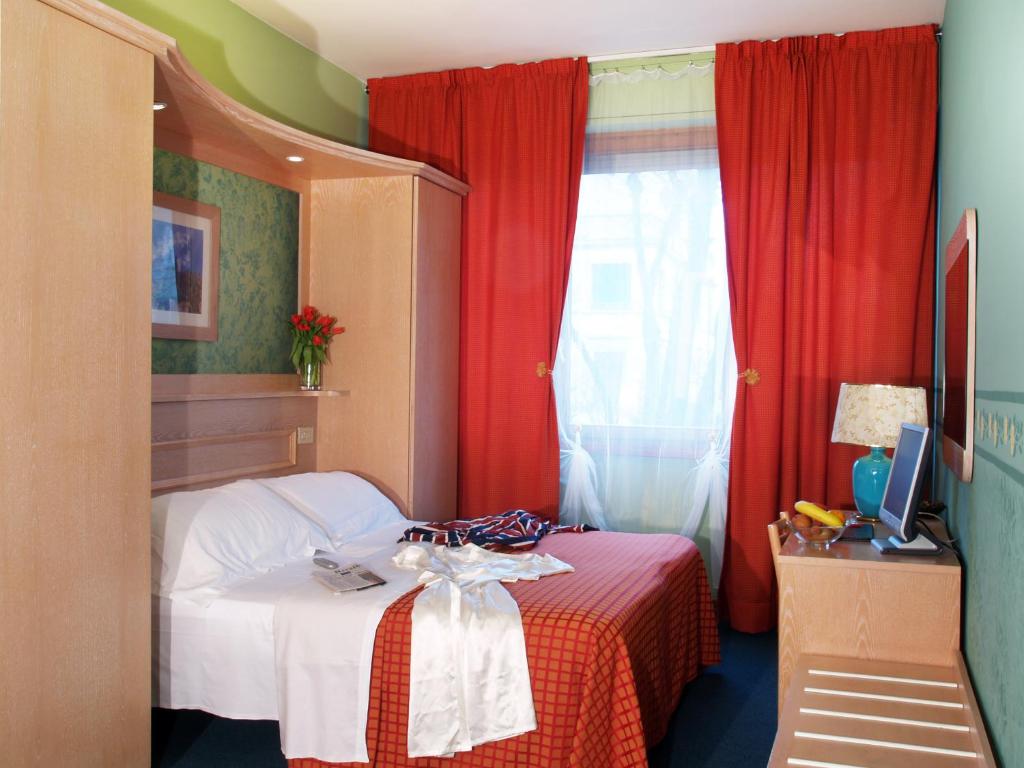 a small bedroom with a bed with red curtains at Hotel Meridiana in Florence