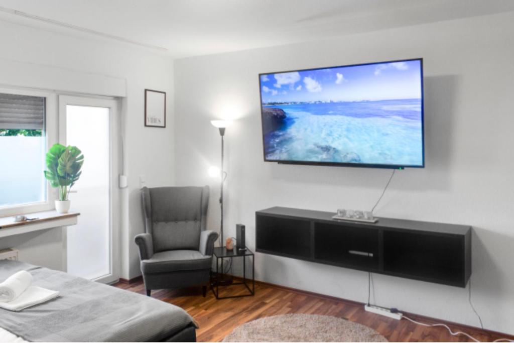 sala de estar con TV de pantalla plana en la pared en Relax Oasis with 65 SmartTV, Kitchen and Balcony, en Duisburg