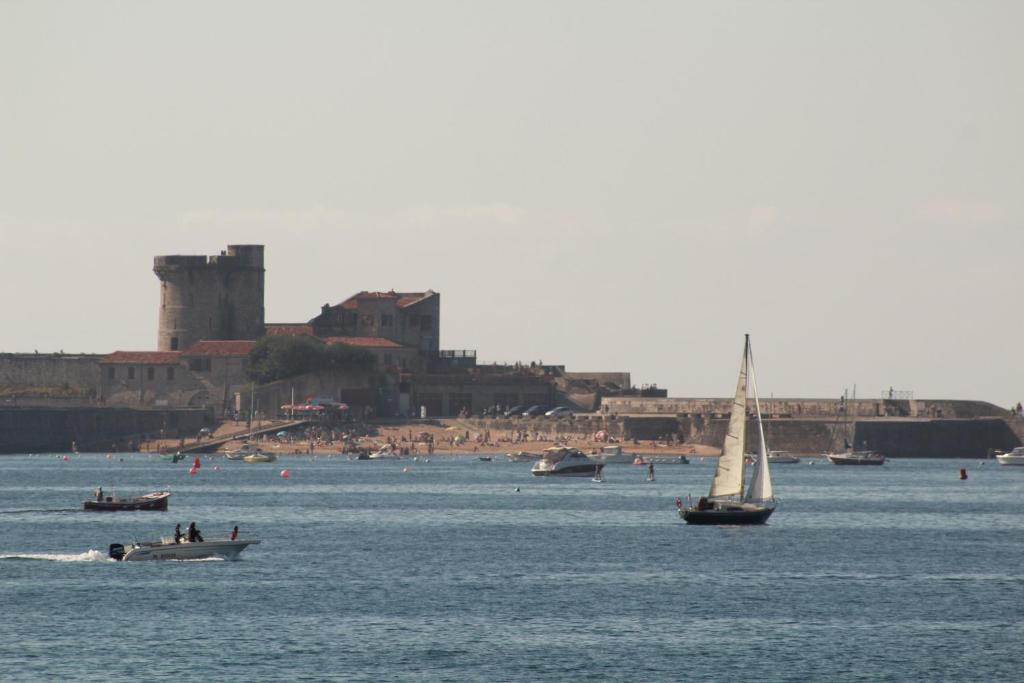 a sail boat in the water with a castle in the background at Hotel Bel Air in Saint-Jean-de-Luz