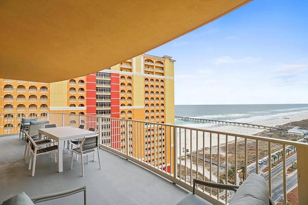 a balcony with a table and chairs and a view of the beach at Calypso 3-1601 - Corine's Corner in Panama City Beach