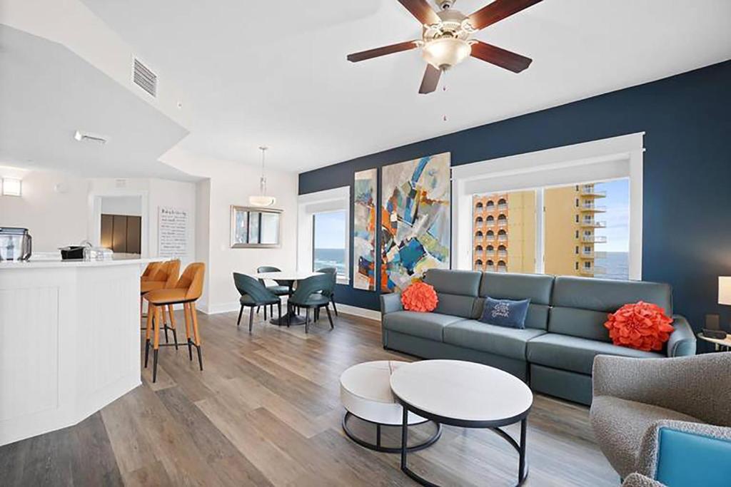 a living room with a couch and tables and a kitchen at Calypso 3-1601 - Corine's Corner in Panama City Beach