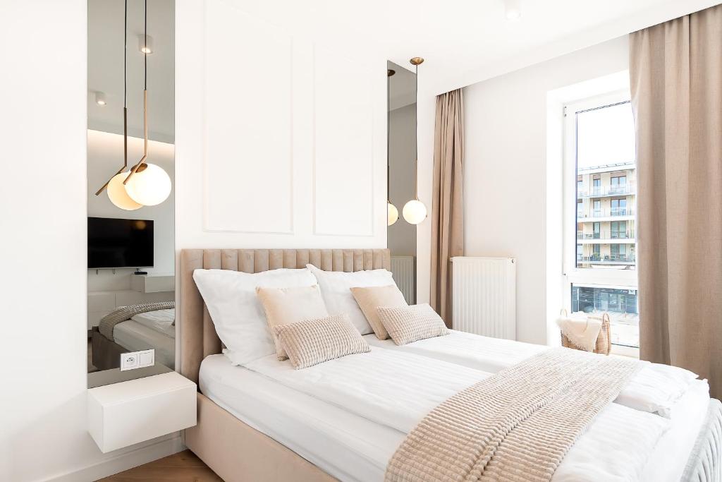 a white bedroom with a large bed and a window at City break apartment Kraków in Krakow