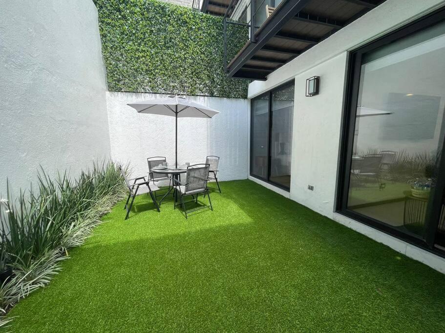 un patio con mesa y sillas con césped verde en Excelente departamento c/jardín., en Ciudad de México