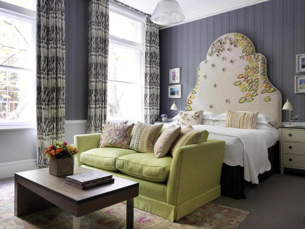 1 dormitorio con 1 cama y 1 sofá verde en Covent Garden Hotel, Firmdale Hotels, en Londres