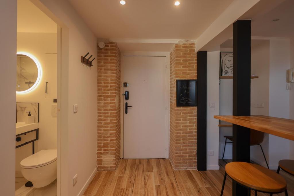 a bathroom with a white toilet and a brick wall at Villa Corbelle - Grand Studio in Cannes