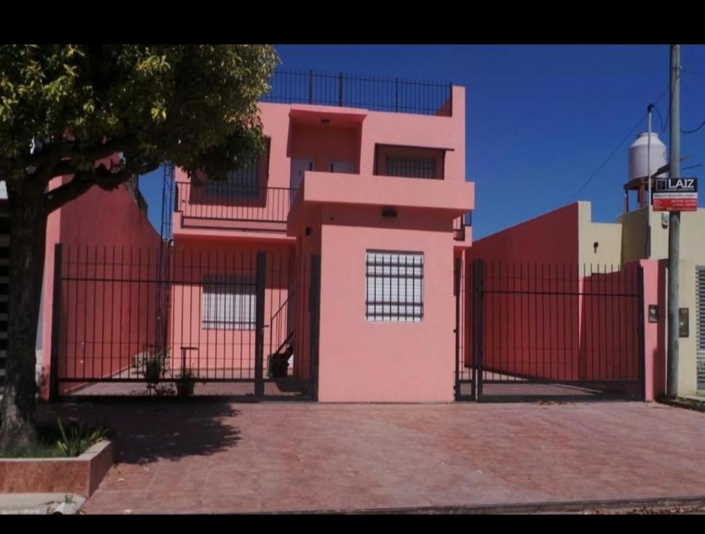 un edificio rosa con una valla roja delante de él en Catamarca Apart en Ramallo
