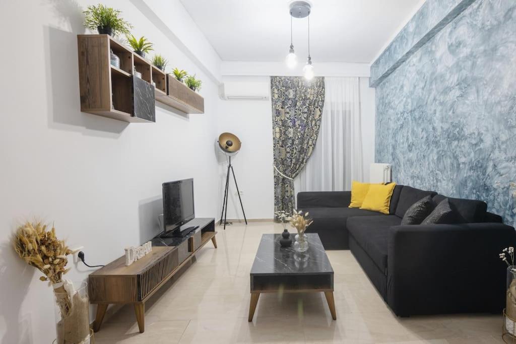 ein Wohnzimmer mit einem schwarzen Sofa und einem Tisch in der Unterkunft The House Project in Athen