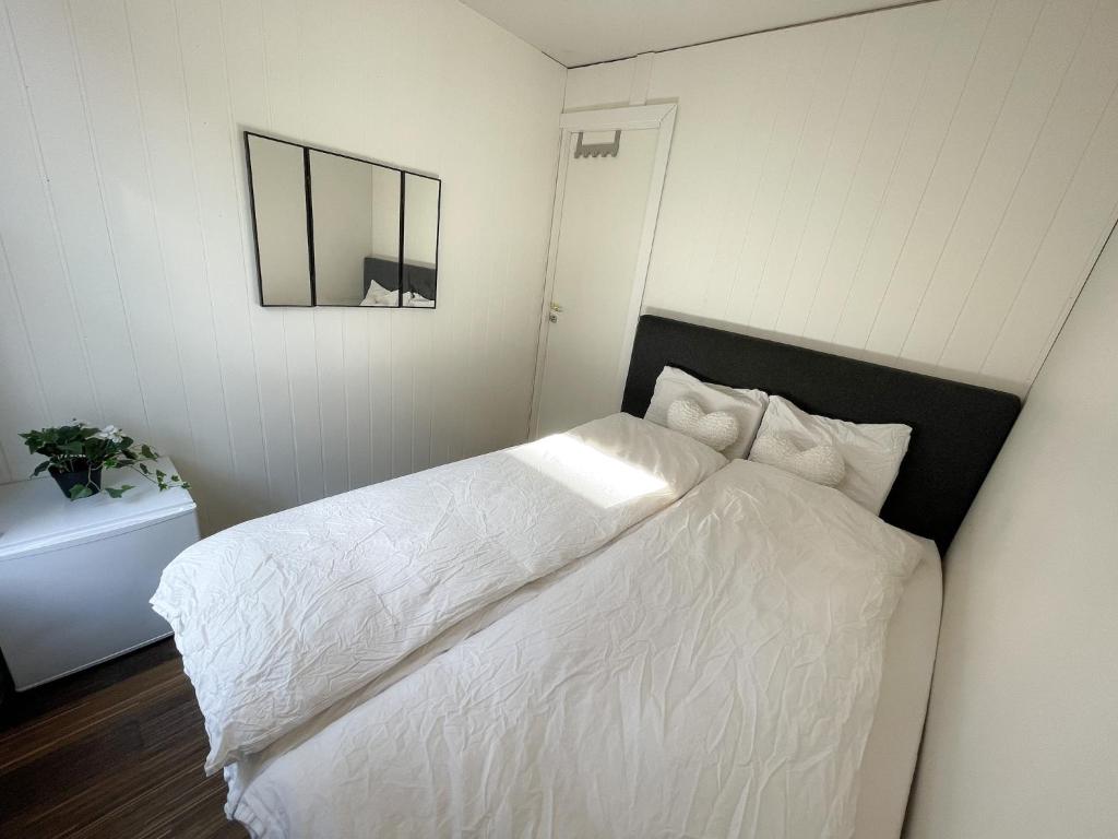 Schlafzimmer mit einem weißen Bett und einem Spiegel in der Unterkunft Pallace House in Oslo
