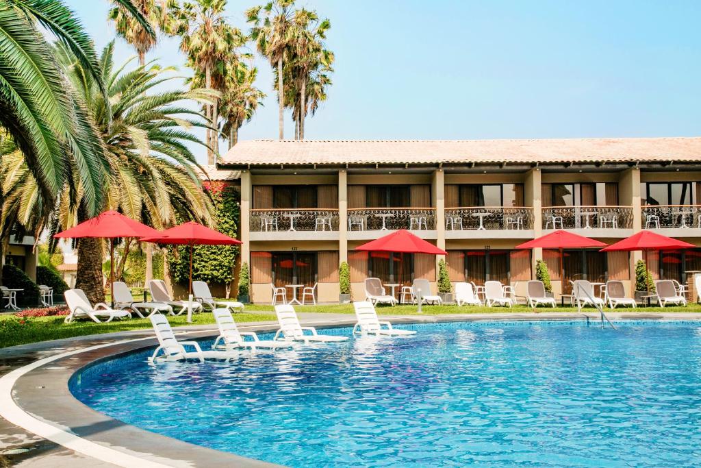 a resort with a swimming pool with chairs and umbrellas at Costa del Sol Wyndham Trujillo in Trujillo