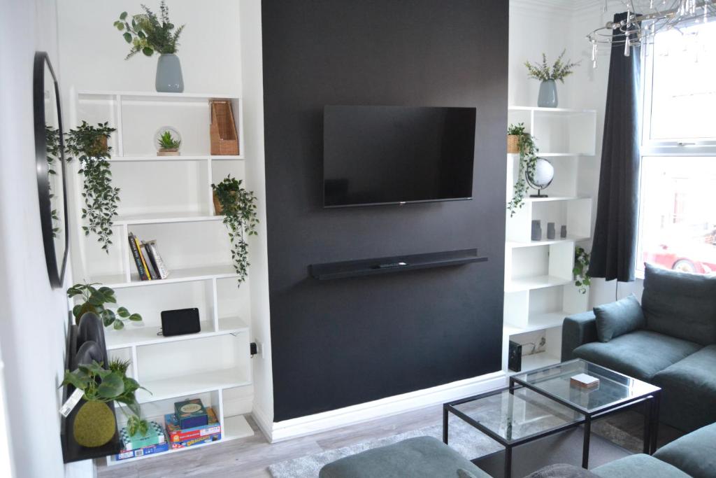 a living room with a couch and a tv on a wall at Luxury Home Close to Leeds City Centre in Leeds