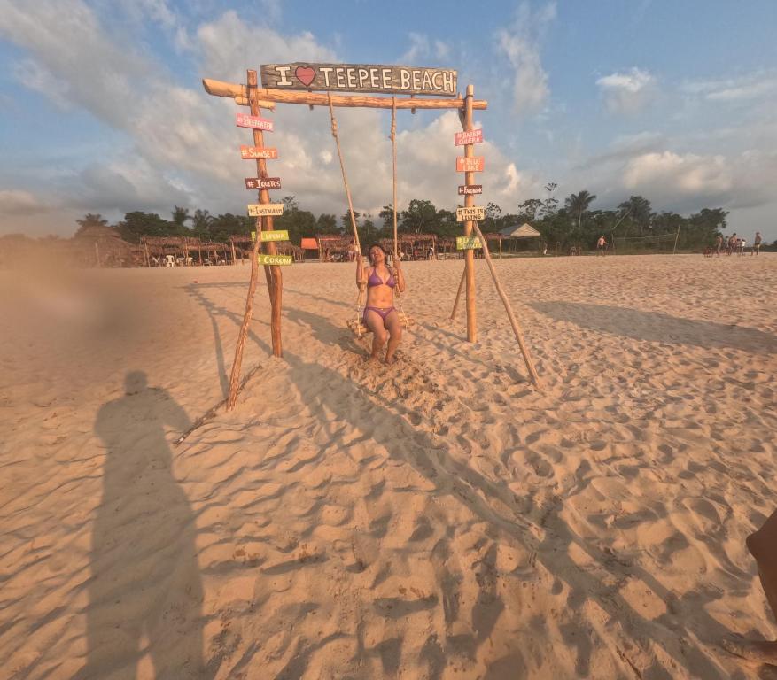 Eine Frau im Bikini steht unter einem Schild am Strand. in der Unterkunft URREAHOUSE IQUITOS in Iquitos