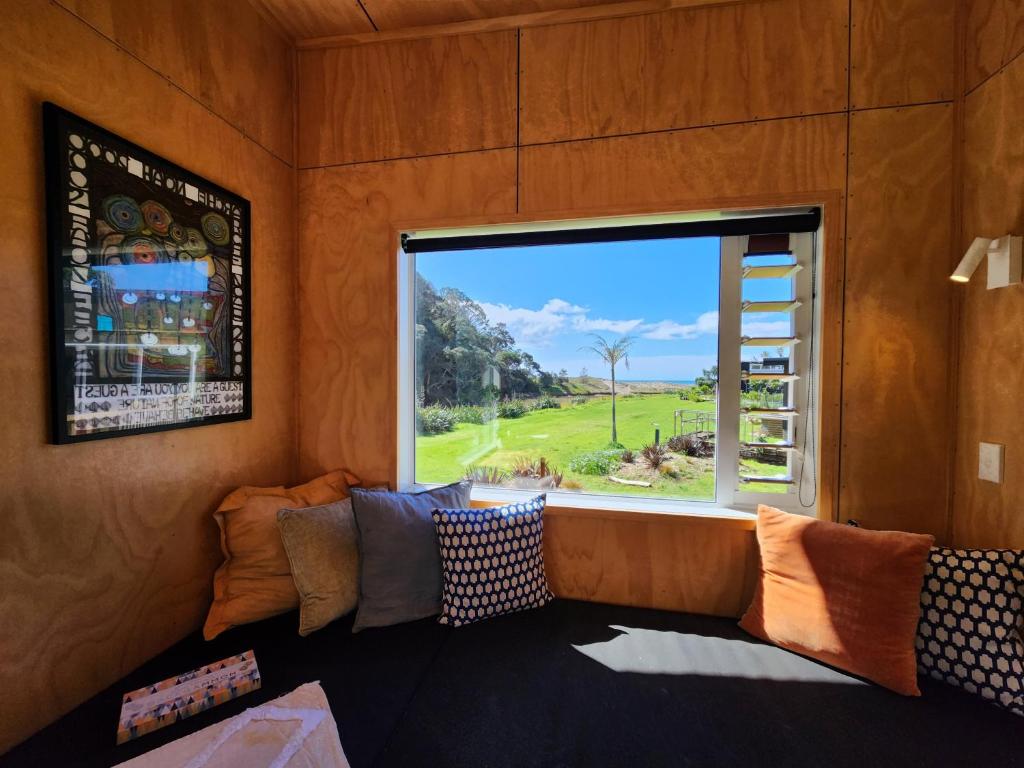 a room with a couch and a large window at Tui Nature Retreat in Hotwater Beach