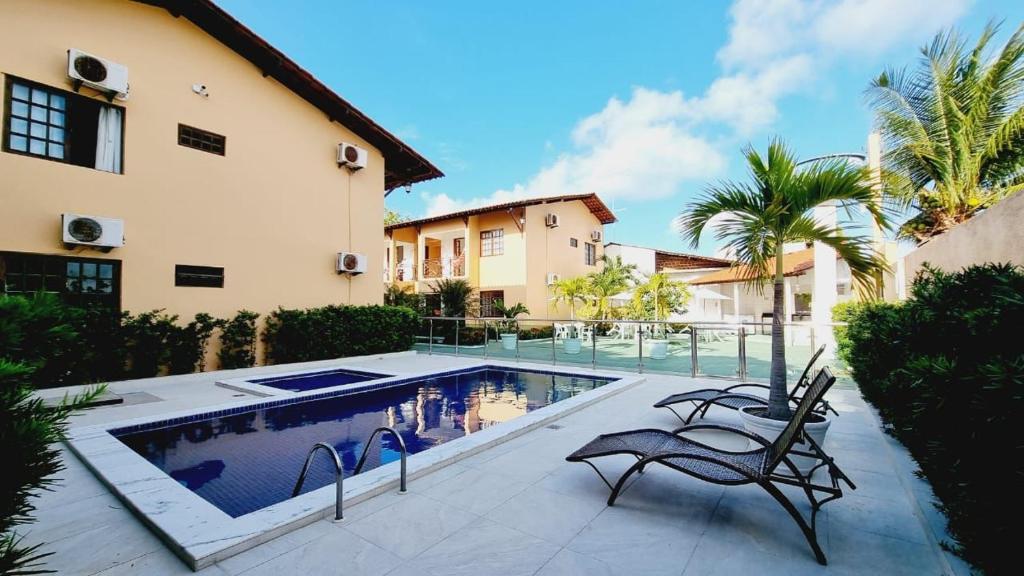 a swimming pool with two chairs next to a house at Condomínio Villa Sossego in Goiana