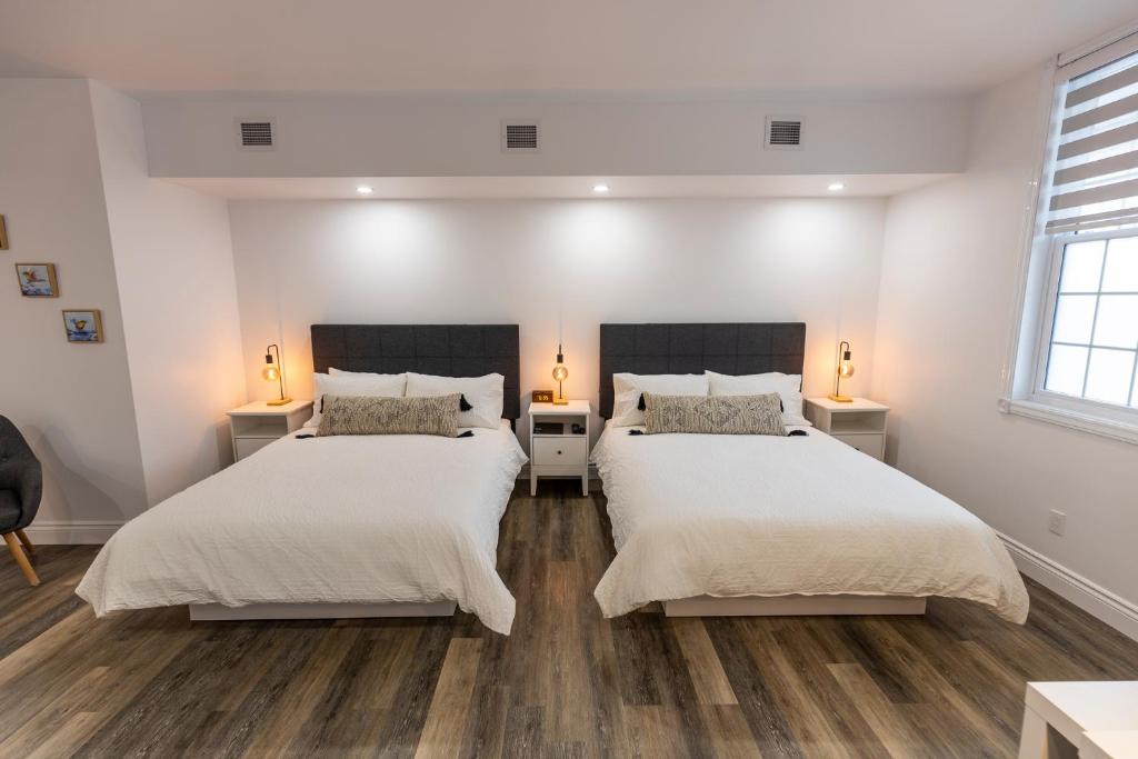 two beds in a bedroom with white walls and wooden floors at Auberge Nouvelle-France in Ville-Marie