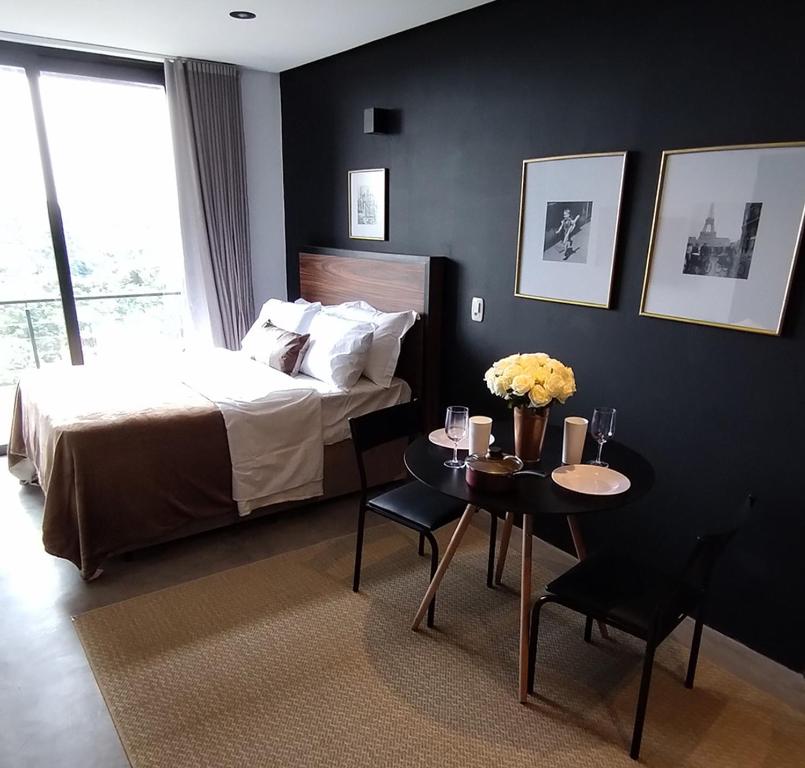 Un dormitorio con una cama y una mesa con flores. en Suites nas Nuvens Premium, en Gramado