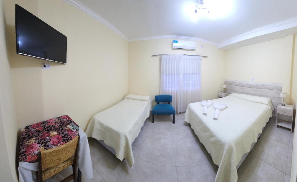 Habitación con 2 camas y TV en la pared. en Hotel Gran Habana en Termas de Río Hondo