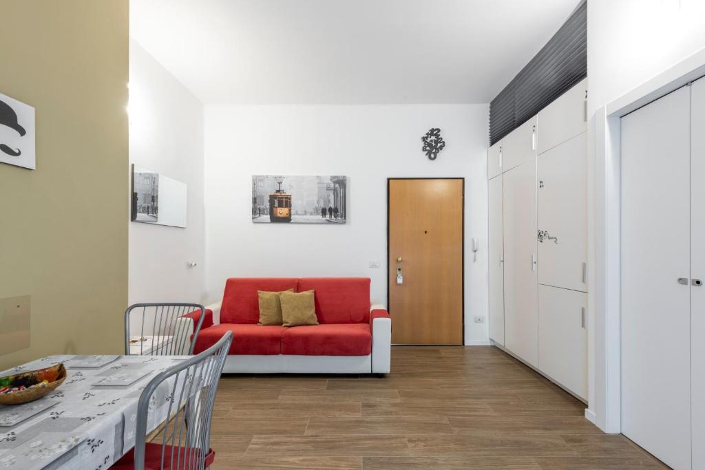 Lucky Flat, un momento di relax. في ميلانو: غرفة معيشة مع أريكة حمراء وطاولة