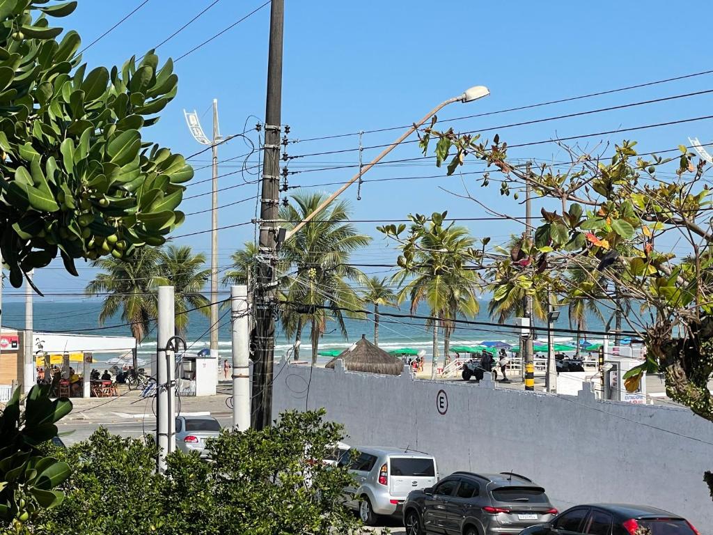 una strada con auto parcheggiate su una spiaggia con palme di Blue Hale a Guarujá