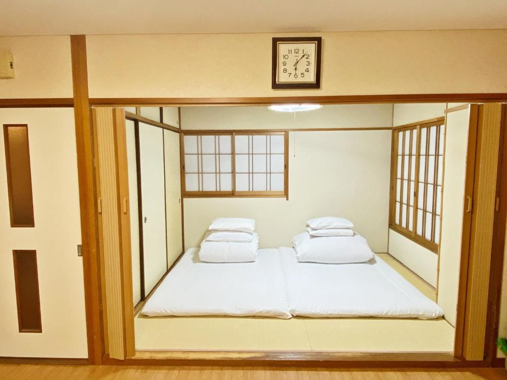 twee bedden in een kamer met een klok aan de muur bij Reynaville 4F / Vacation STAY 3339 in Tokushima