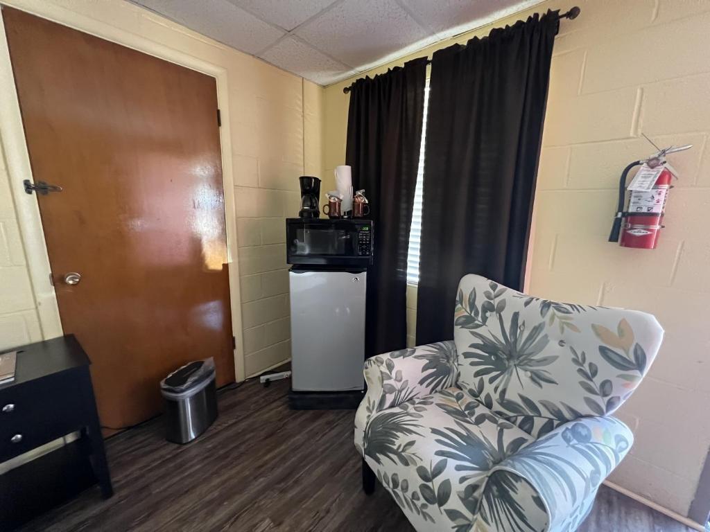 a living room with a chair and a refrigerator at JI4, King Guest Room at the Joplin Inn at entrance to the resort Hotel Room in Mount Ida