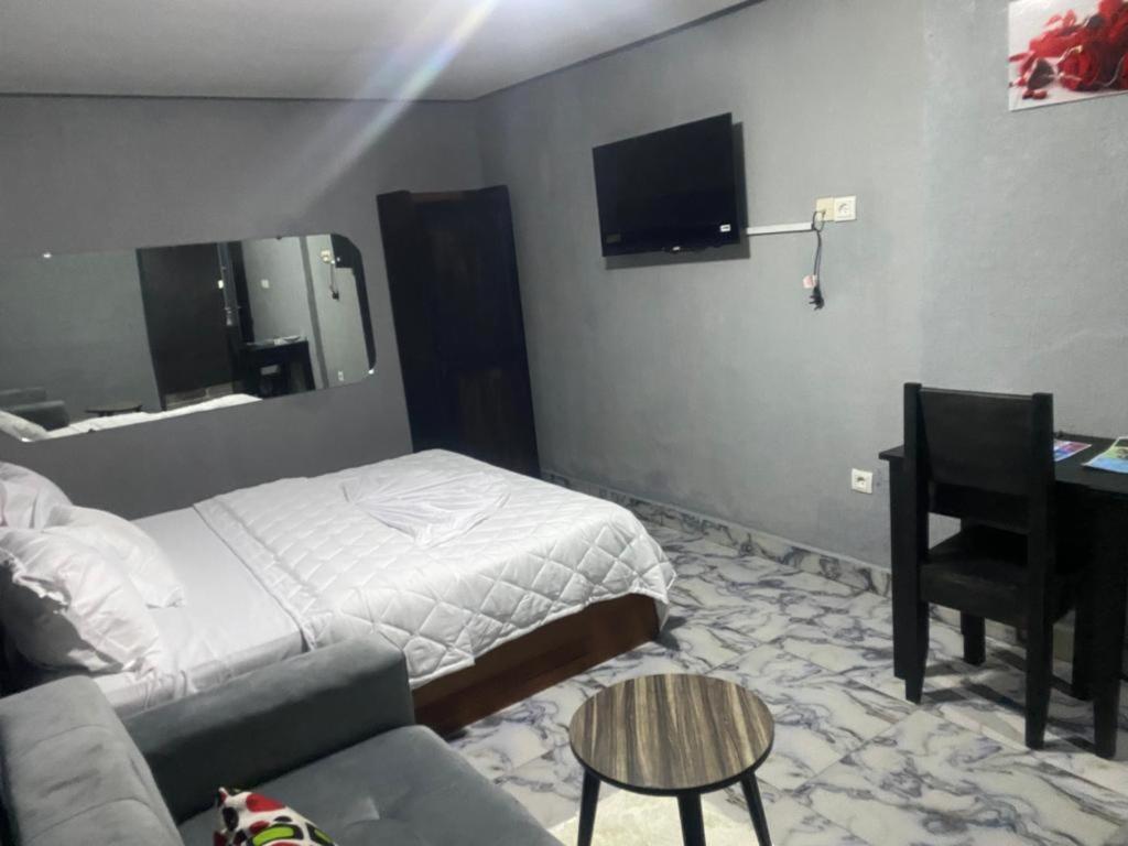 - une chambre avec un lit, un bureau et un canapé dans l'établissement Sunrise Center Bonapriso, à Douala