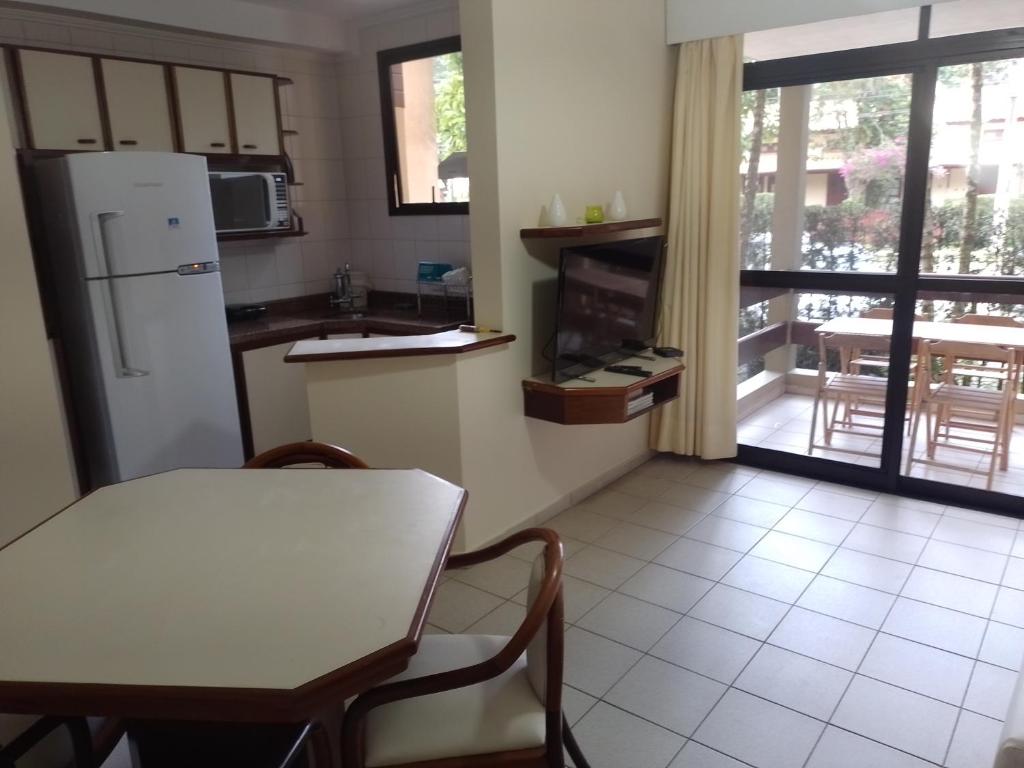 uma cozinha com uma mesa e um frigorífico branco em Riviera Green Residence 232 em Bertioga