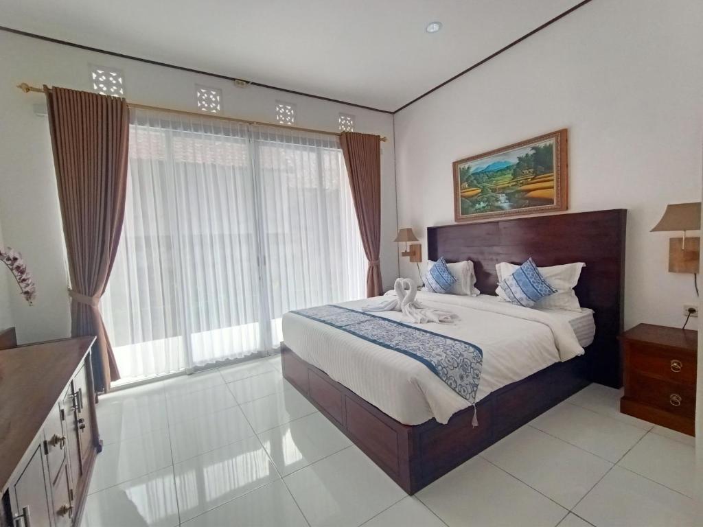 a bedroom with a large bed and a large window at Edu Hotel (Hotel Edukasi SMK PK) in Bangli