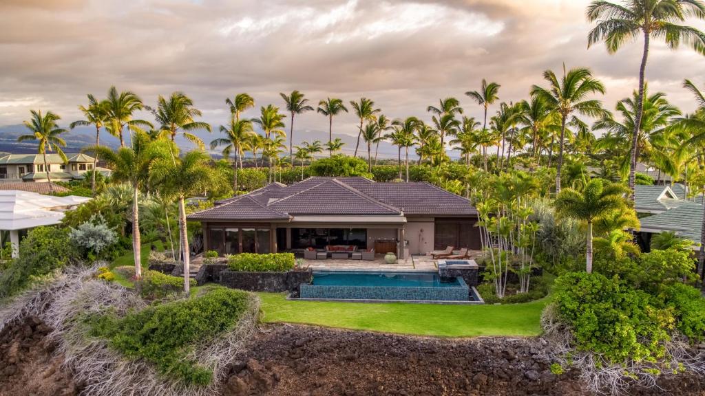 ワイコロアにあるMauna Lani Luxury Vacation Villas - CoralTree Residence Collectionのヤシの木とスイミングプールのある家の空中を望む